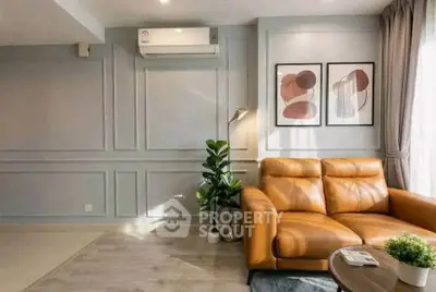 Stylish living room with leather sofa, modern art, and natural light.