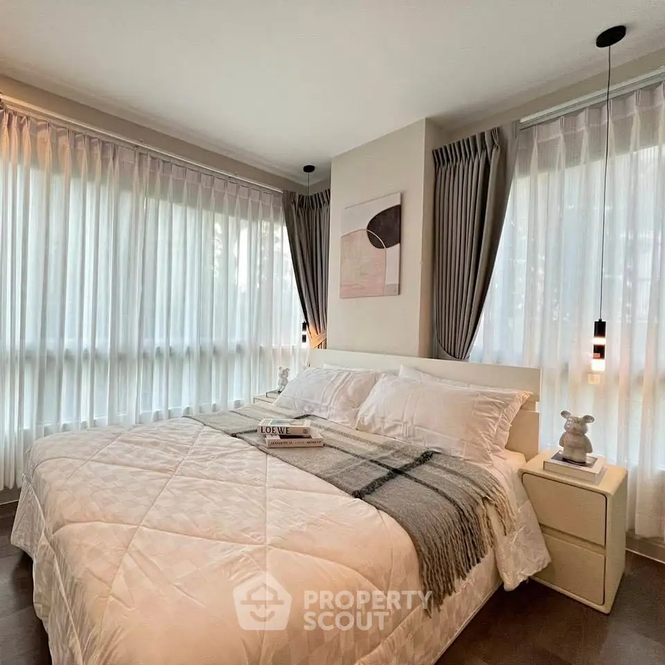 Elegant bedroom with large windows and modern decor, featuring cozy bedding and stylish lighting.