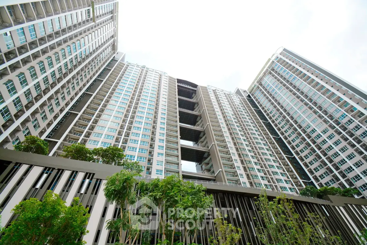 Stunning modern high-rise apartment building with lush greenery and sleek architecture.