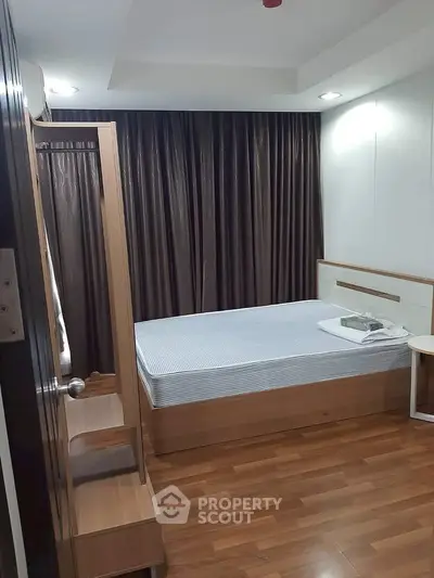 Modern bedroom with wooden flooring and elegant curtains in a cozy apartment.