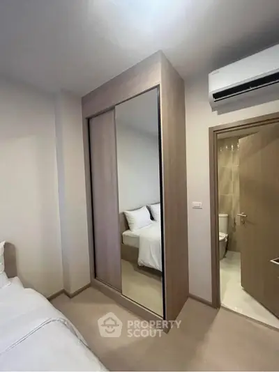 Modern bedroom with mirrored wardrobe and ensuite bathroom in a cozy apartment.