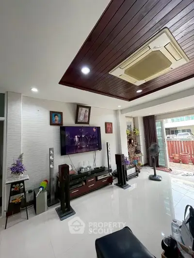 Spacious living room with modern decor and entertainment setup, featuring a large TV and elegant ceiling design.