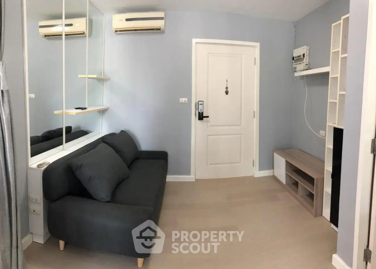 Modern living room with sleek gray sofa and wall-mounted air conditioning unit.