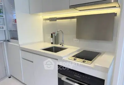 Modern compact kitchen with sleek white cabinetry and built-in appliances, ideal for urban living.