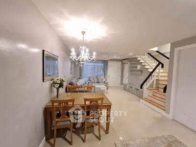 Elegant open-plan living and dining area with chandelier and staircase, perfect for modern family living.