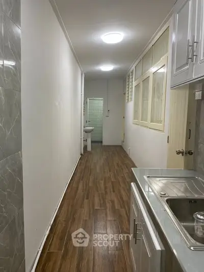 Narrow kitchen with wooden flooring and sleek cabinetry in a modern apartment