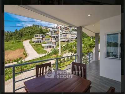 Stunning balcony view of modern hillside villas with lush greenery and clear blue skies.