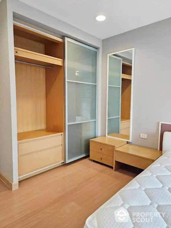 Modern bedroom with sliding wardrobe and wooden flooring