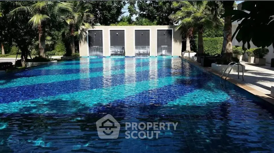 Luxurious outdoor pool with cascading water features and lush greenery.