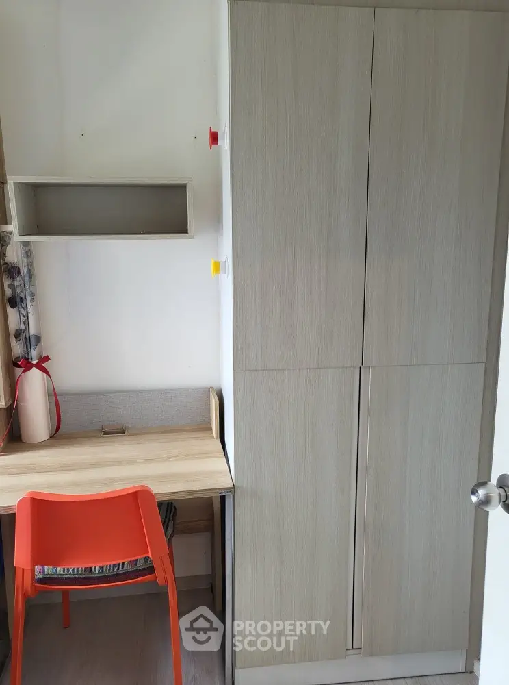 Compact study area with wooden desk and bright orange chair