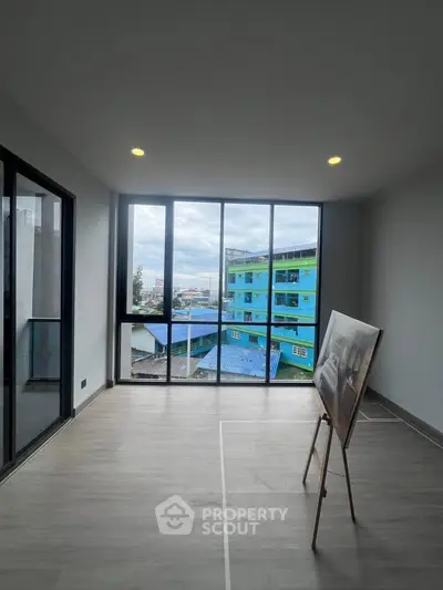 Spacious modern living room with large windows offering city views, perfect for urban living.