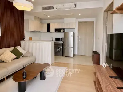 Modern open-plan living room with kitchen, featuring stylish furniture and appliances.