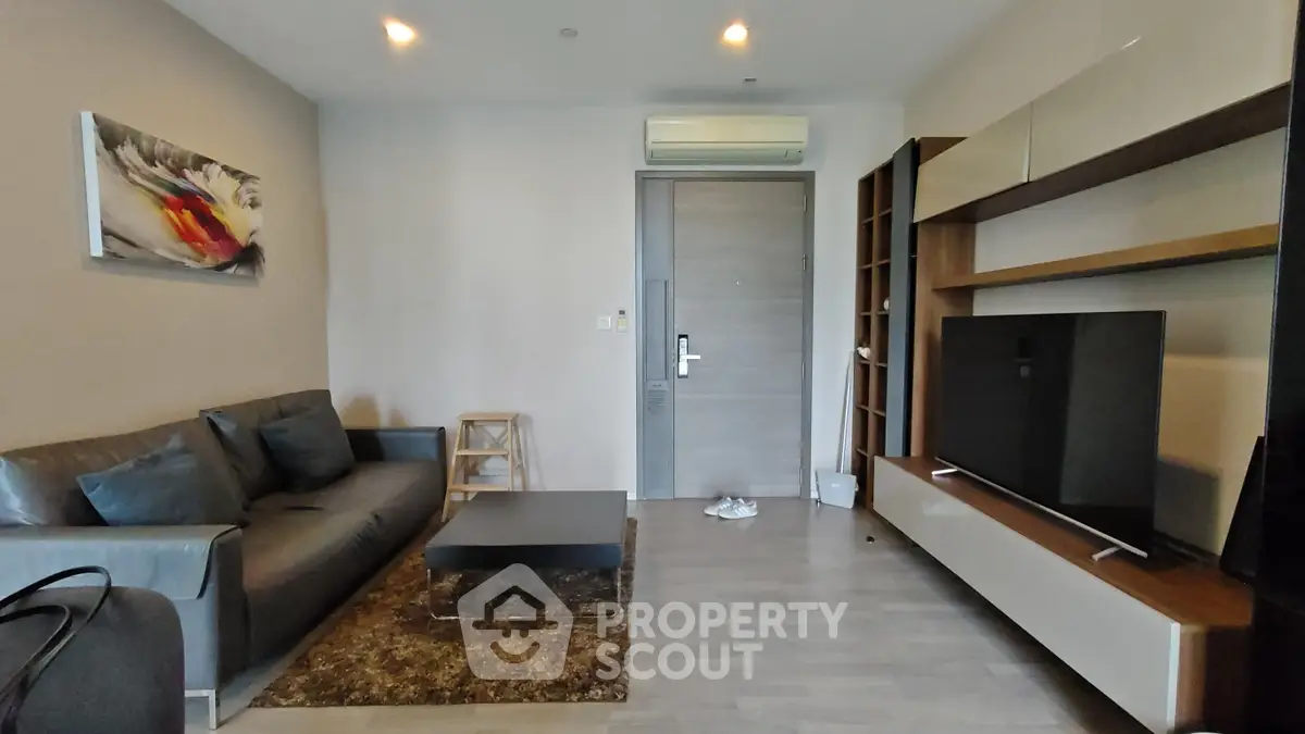 Modern living room with sleek furniture and wall-mounted TV in a stylish apartment.