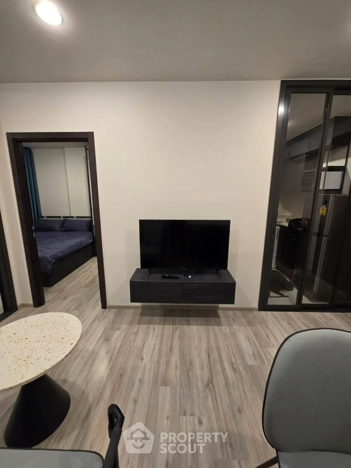 Modern living room with sleek TV setup and view into bedroom