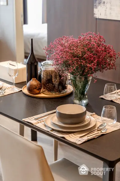 Elegant dining table setup with modern decor and floral centerpiece in stylish apartment.