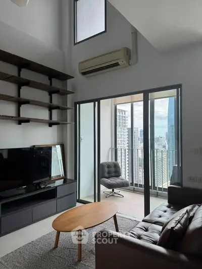 Modern living room with balcony and city view, featuring sleek furniture and high ceilings.