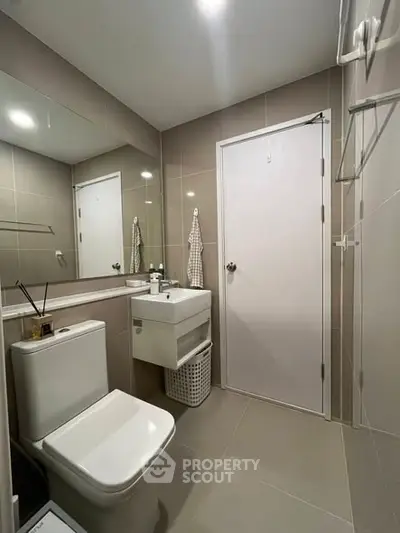 Modern bathroom with sleek fixtures and neutral tiles, featuring a compact design.