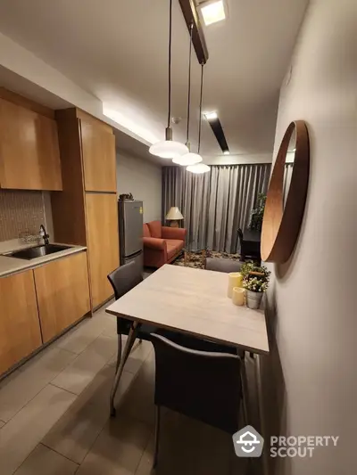 Modern kitchen with sleek wooden cabinets and stainless steel appliances opens to a cozy dining area, perfect for intimate dinners or casual breakfasts.