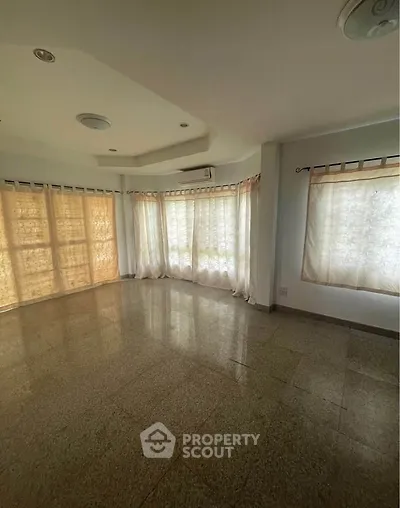 Spacious sunlit living room with large windows and elegant ceiling design.