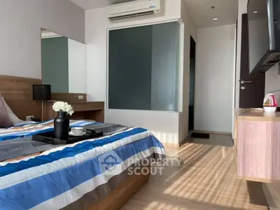 Modern bedroom with stylish decor and natural light, featuring a cozy bed and sleek furnishings.