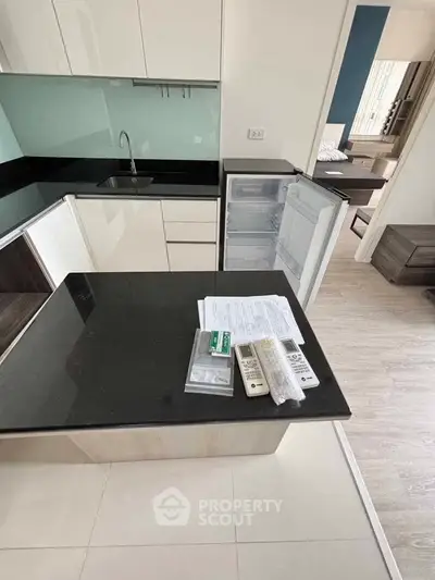 Modern kitchen with sleek black countertops and open fridge in stylish apartment.