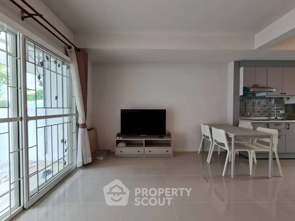 Modern living room with TV, dining area, and open kitchen layout in bright apartment.