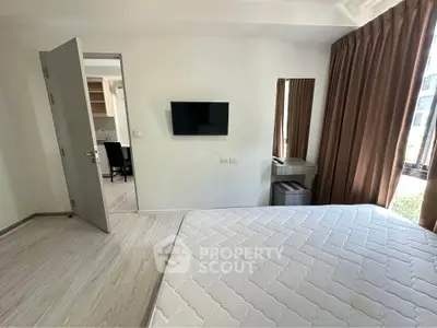 Modern bedroom with wall-mounted TV and large window for natural light