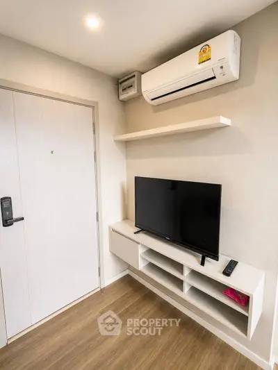 Modern living room with sleek TV setup and air conditioning in a cozy apartment.