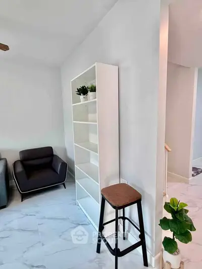 Modern living room with sleek armchair and minimalist bookshelf on marble flooring.