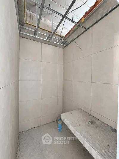 Unfinished bathroom with tiled walls and exposed ceiling in a new construction project.