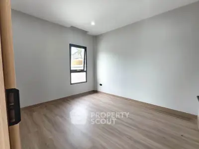 Spacious empty room with wooden flooring and natural light, perfect for customization.