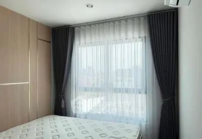 Modern bedroom with large window and elegant curtains, featuring a comfortable mattress and sleek wooden wardrobe.