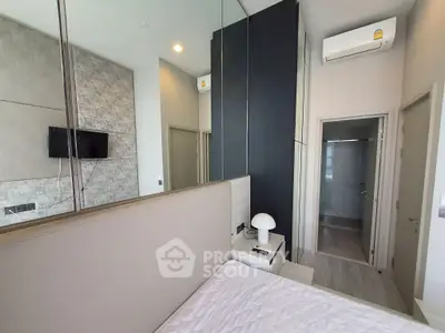 Modern bedroom with sleek design, featuring a wall-mounted TV, air conditioning, and stylish decor.