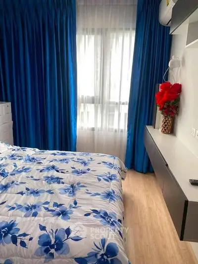 Cozy bedroom with floral bedding and vibrant blue curtains, perfect for a serene retreat.