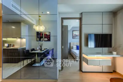 Modern open-plan living room with stylish dining area and bedroom view, featuring sleek furniture and elegant decor.