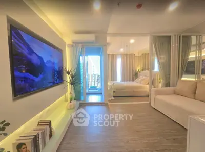 Modern open-layout living room with stylish decor and a view into a cozy bedroom, featuring elegant furnishings.