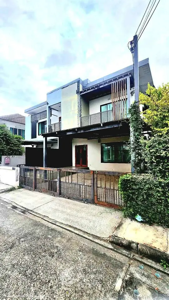 Modern two-story house with sleek design and spacious balcony in a suburban neighborhood.