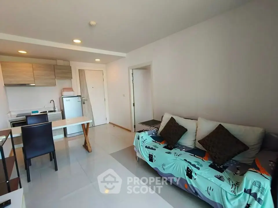 Modern open-layout living room with kitchen, featuring stylish decor and natural light.