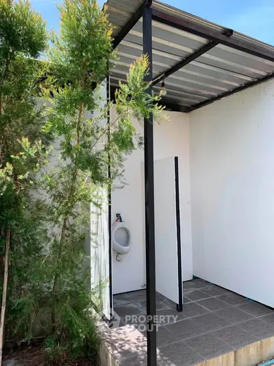Outdoor urinal area with privacy partitions and greenery, ideal for commercial or public spaces.