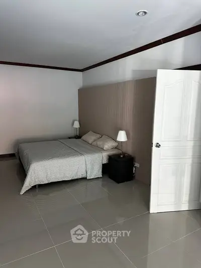 Spacious bedroom with modern design and neutral tones, featuring a cozy bed and elegant bedside lamps.