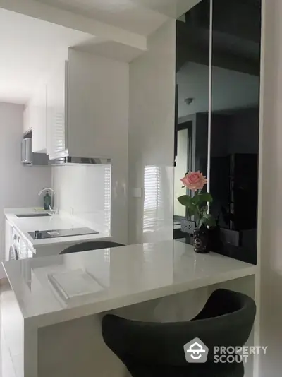 Modern kitchen with sleek white countertops and black accents, featuring a stylish breakfast bar and elegant decor.