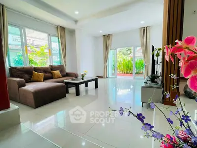 Spacious living room with modern decor and large windows offering garden views.