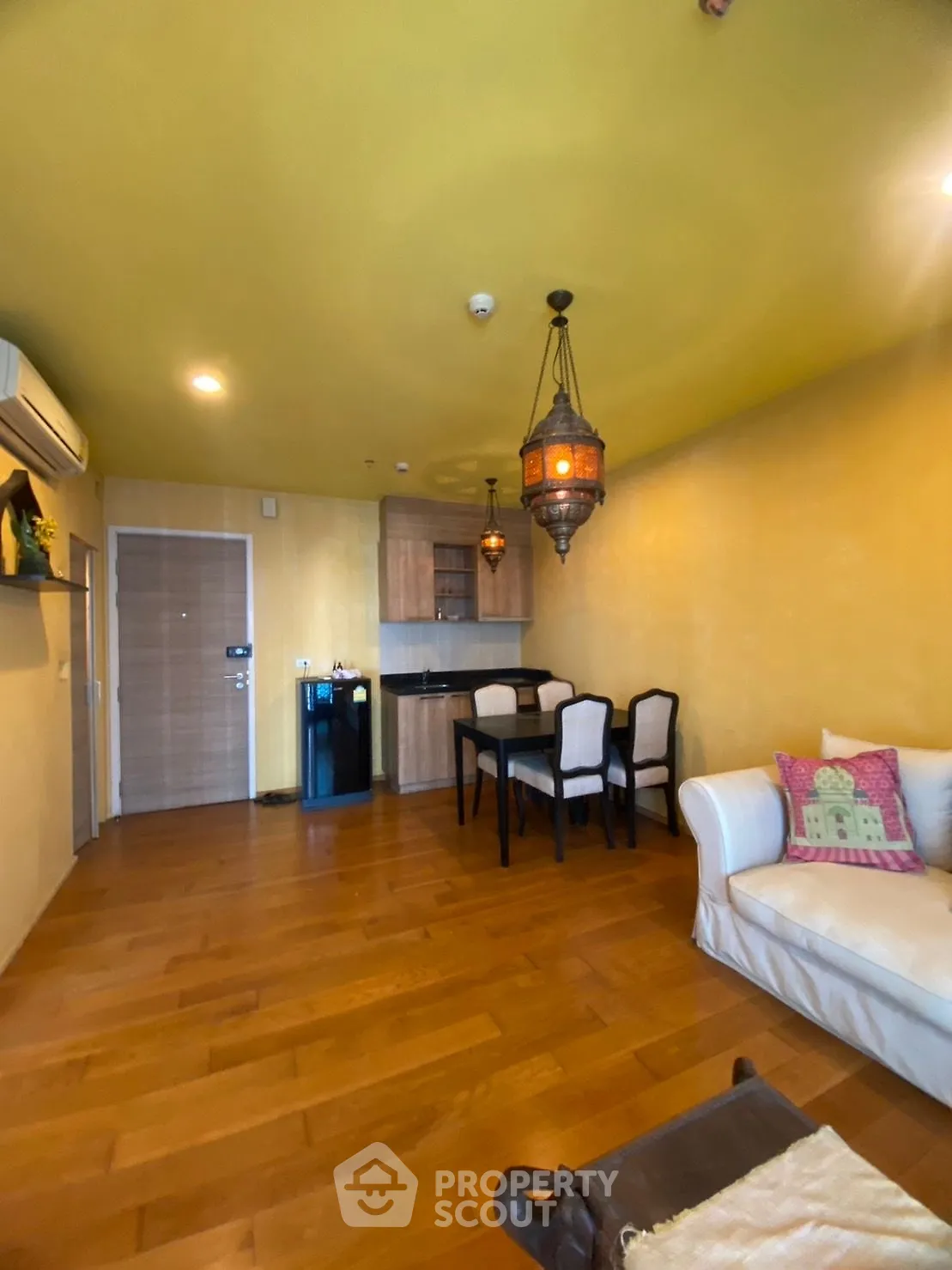 Charming living room with warm wooden flooring and elegant dining area, featuring cozy seating and ambient lighting.