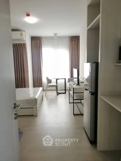Modern studio apartment with natural light, featuring a compact kitchen and cozy living area.