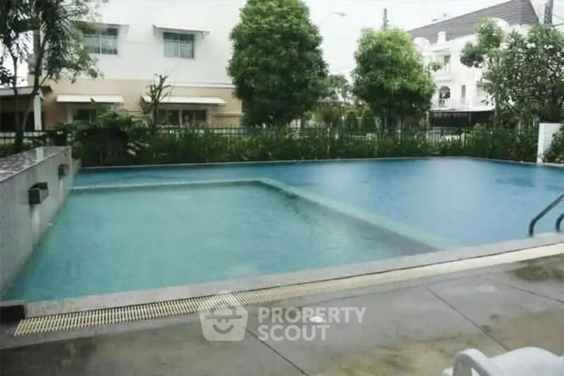 Luxurious residential pool area with lush greenery and modern architecture.