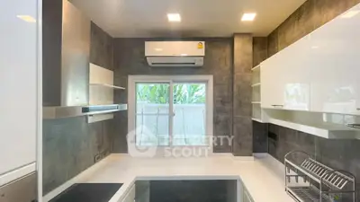 Modern kitchen with sleek cabinetry and air conditioning, featuring a large window for natural light.