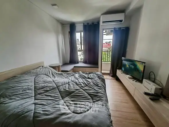 Modern bedroom with balcony view, featuring sleek furniture and natural light.