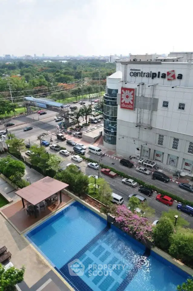 Stunning aerial view of a modern urban pool with lush greenery and cityscape backdrop.
