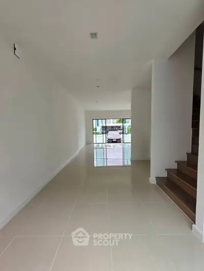 Spacious modern interior with tiled flooring and staircase, perfect for customization.