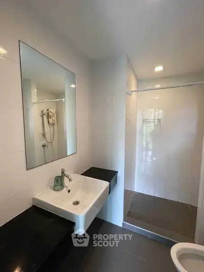 Modern bathroom with sleek sink and spacious shower area in contemporary apartment.